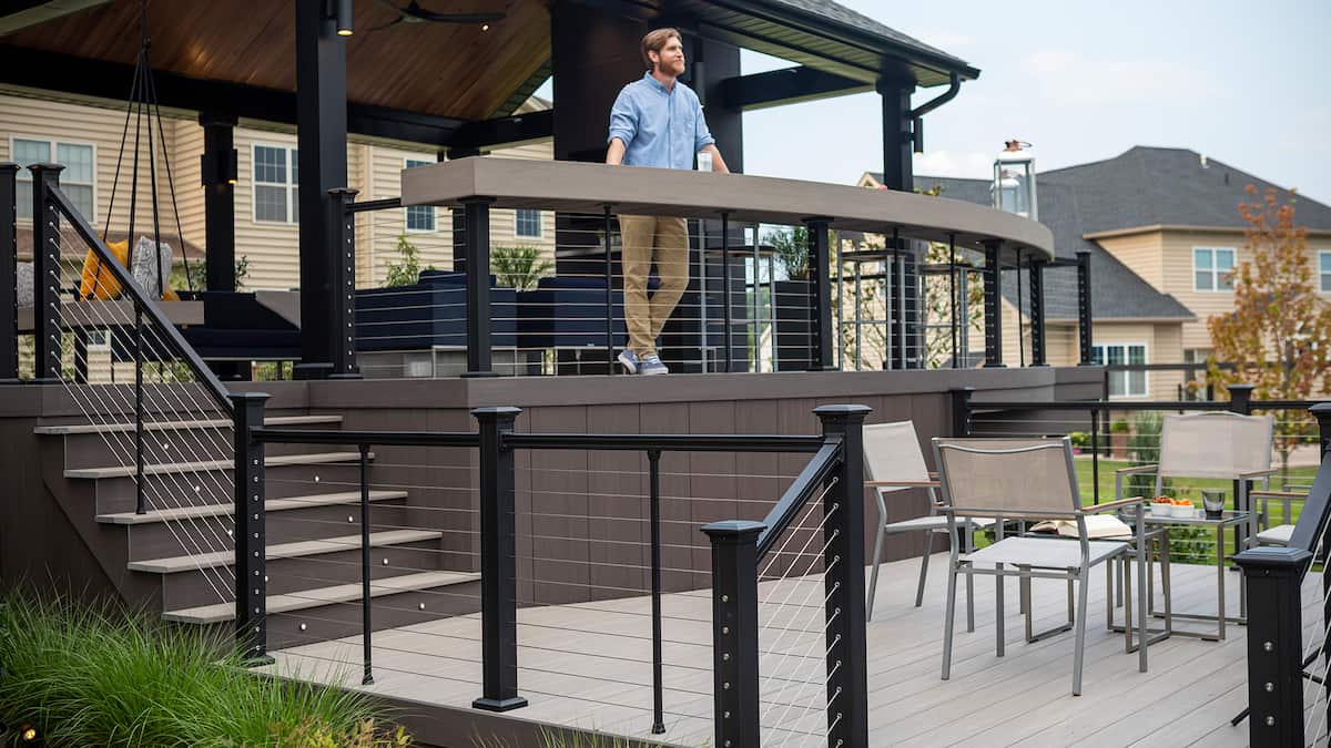 Key-Link American Series Horizontal Cable Rail. A man stands on hist deck looking at his back yard.