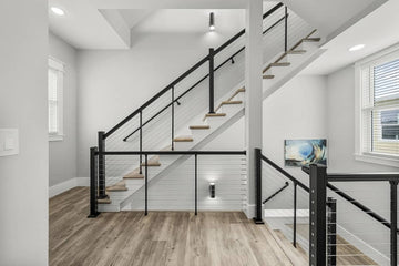 Interior stair with matte black finish and stainless steel cable railing and a continuous secondary handrail.